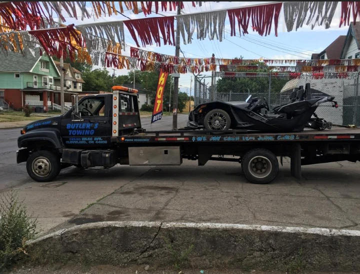 Tow truck carrying a junk car in a city setting.