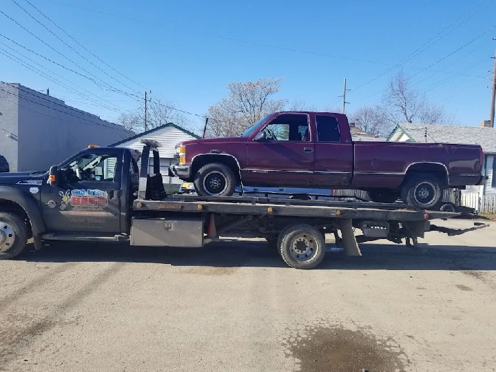 Tow truck carrying a purple pickup truck.