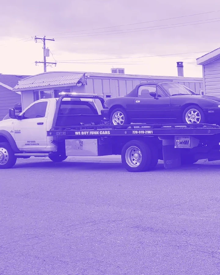 Tow truck hauling a junk car for recycling.