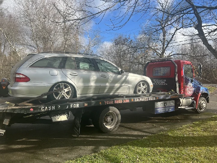 Tow truck transporting a silver car to salvage yard.