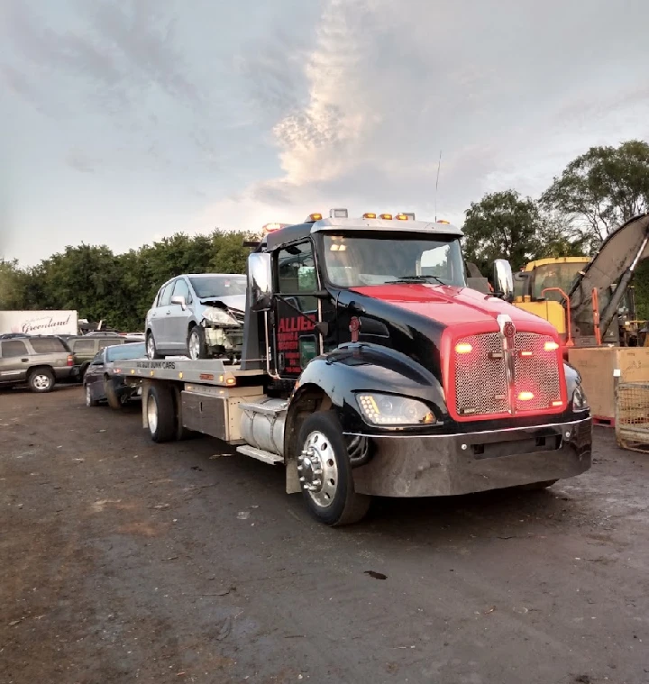 Towing truck carrying a junk car for service.