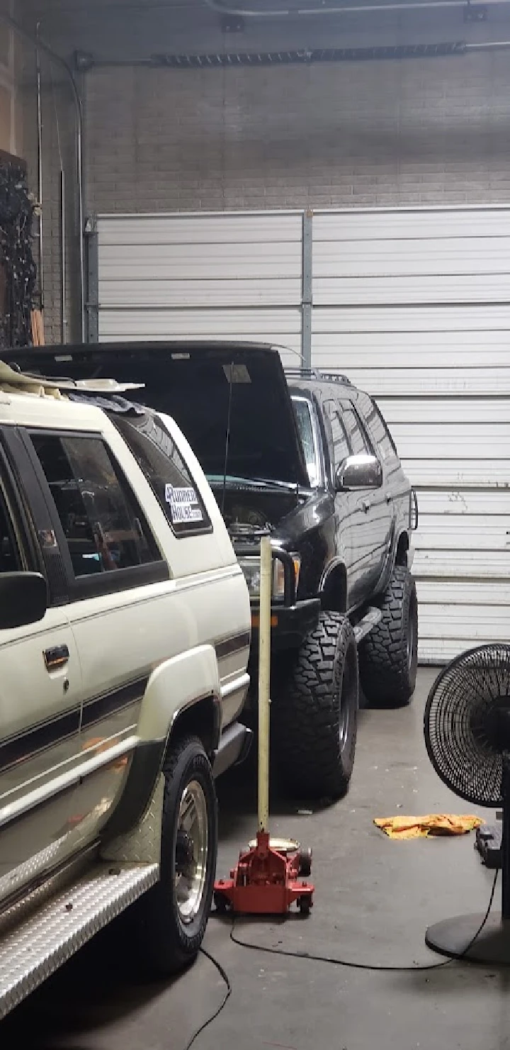 Two 4Runners in a garage, one elevated on a jack.