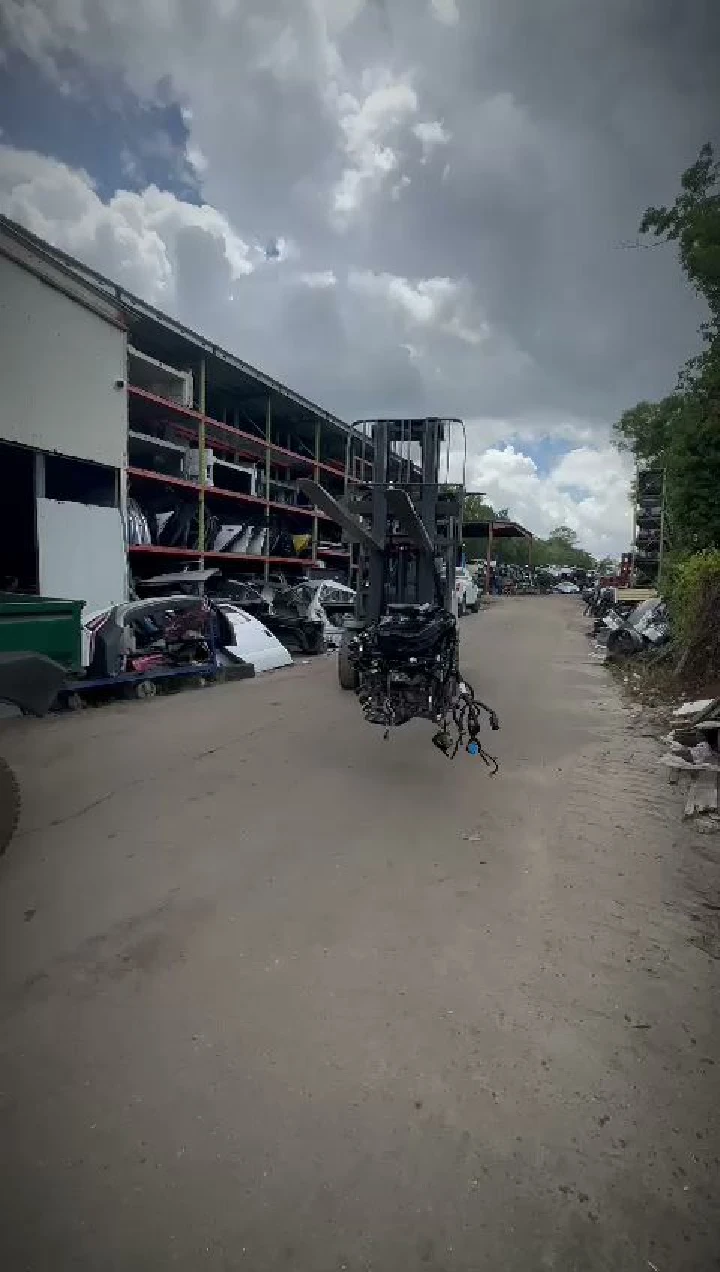 Used auto parts yard with machinery in view.