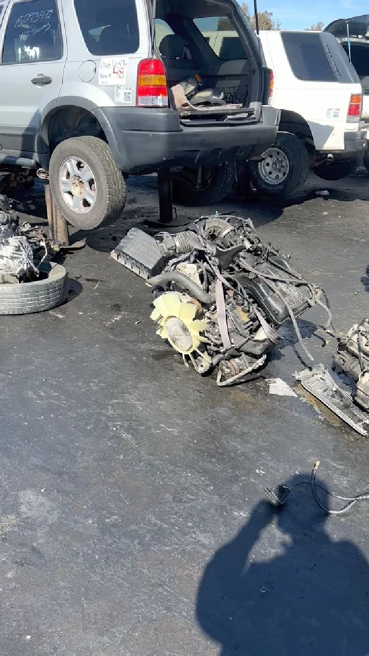 Vehicle parts and an engine in a junkyard.