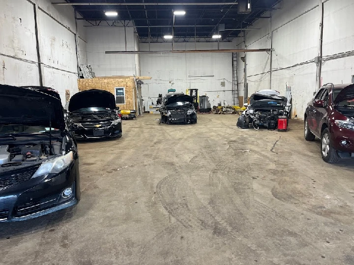 Vehicles with open hoods in a salvage yard.