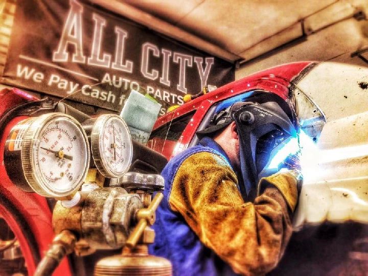 Welder working on a car at All City Auto Parts.