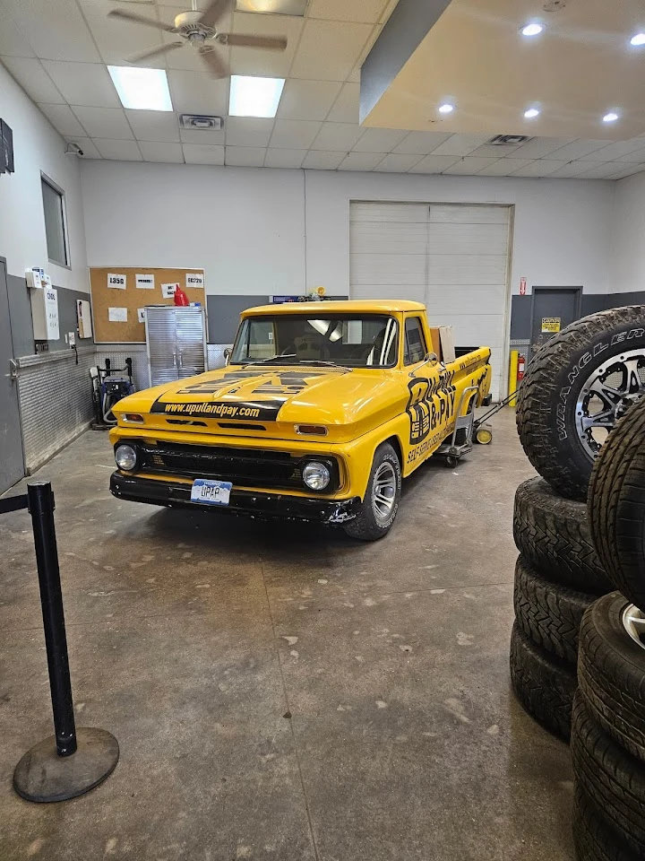 Yellow pickup truck in a garage with tires.