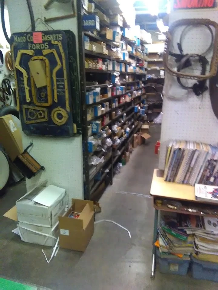 Aisle with shelves of antique auto parts and boxes.