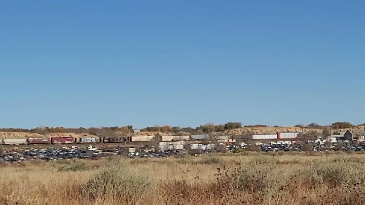 Auto lot with train in background and clear sky.