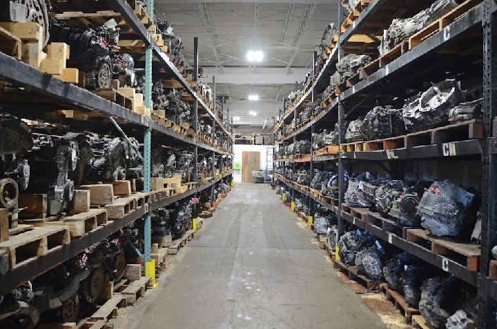 Auto parts warehouse with stacked engines and pallets.