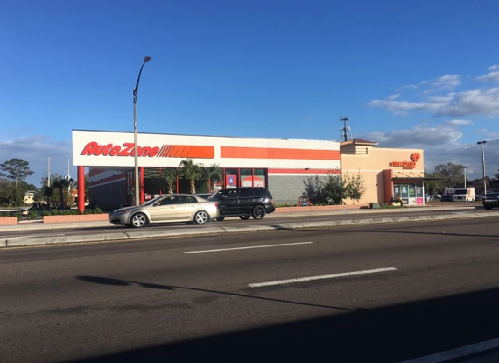 AutoZone store front with parked cars nearby.