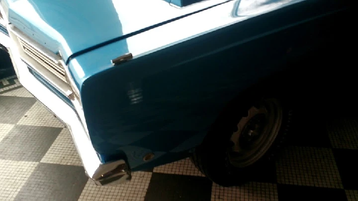 Blue classic car in a garage setting.