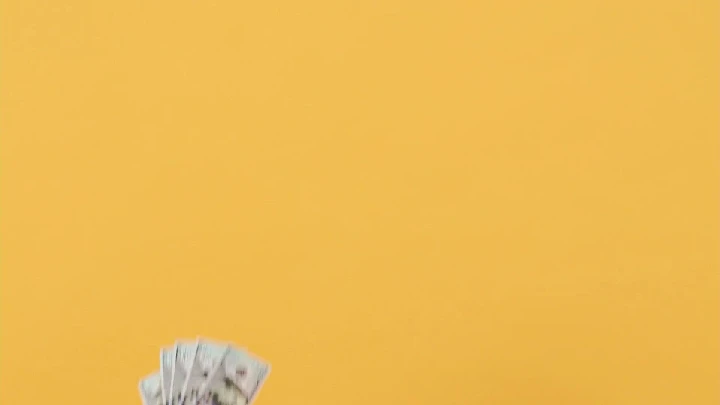 Cash in hand against a yellow background.