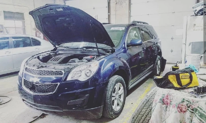 Chevrolet Equinox with hood open in auto shop.