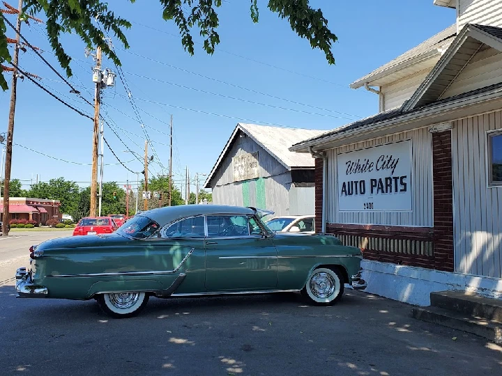 Classic car parked outside White City Auto Parts.