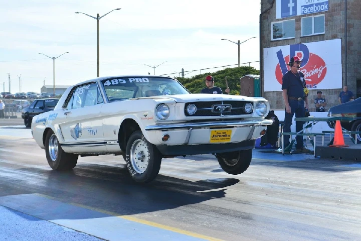 Classic Mustang performing a wheelie at the track.