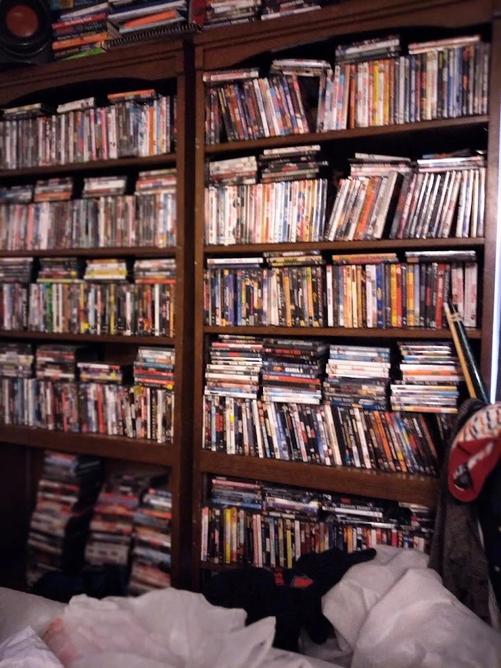 Cluttered shelves filled with numerous DVDs.