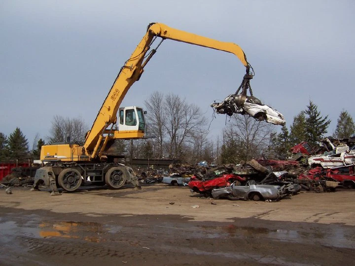 Crane lifting a car at a salvage yard.