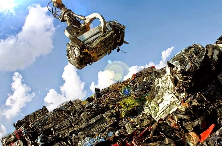 Crane lifting metal from a junkyard of cars.