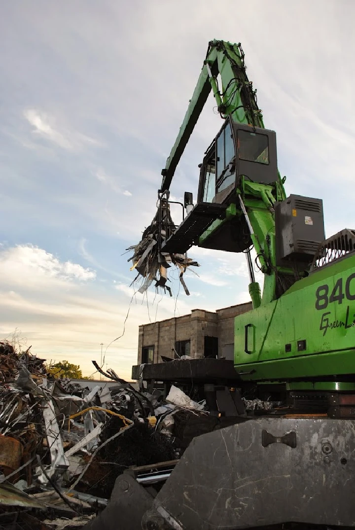 Crane lifting scrap metal at a processing yard.