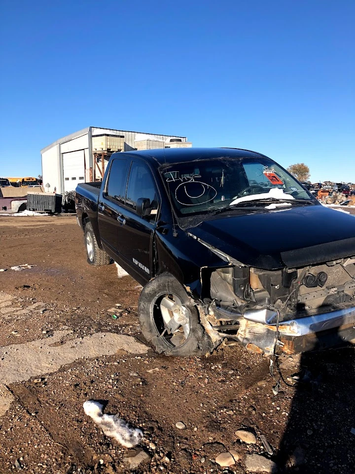 Damaged black pickup truck at salvage yard.