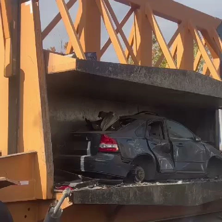 Dismantled car inside yellow industrial machinery.