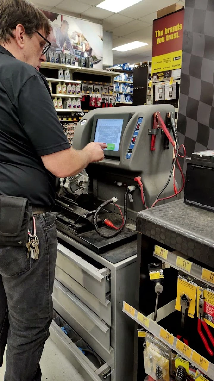 Employee using diagnostic equipment at auto parts store.