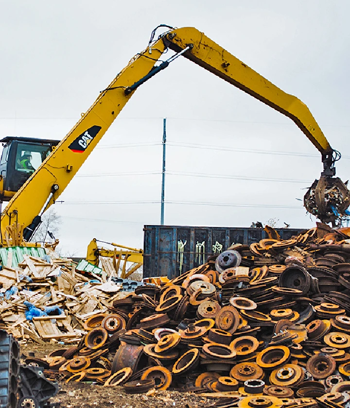 Excavator lifting scraps at a recycling yard.