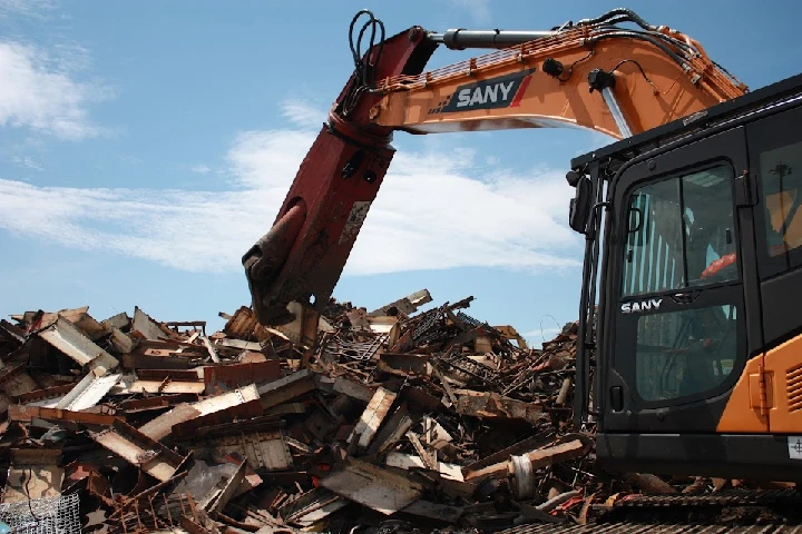 Excavator processing scrap metal at a yard.