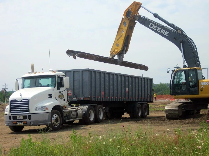 Excavator unloading materials into a truck.