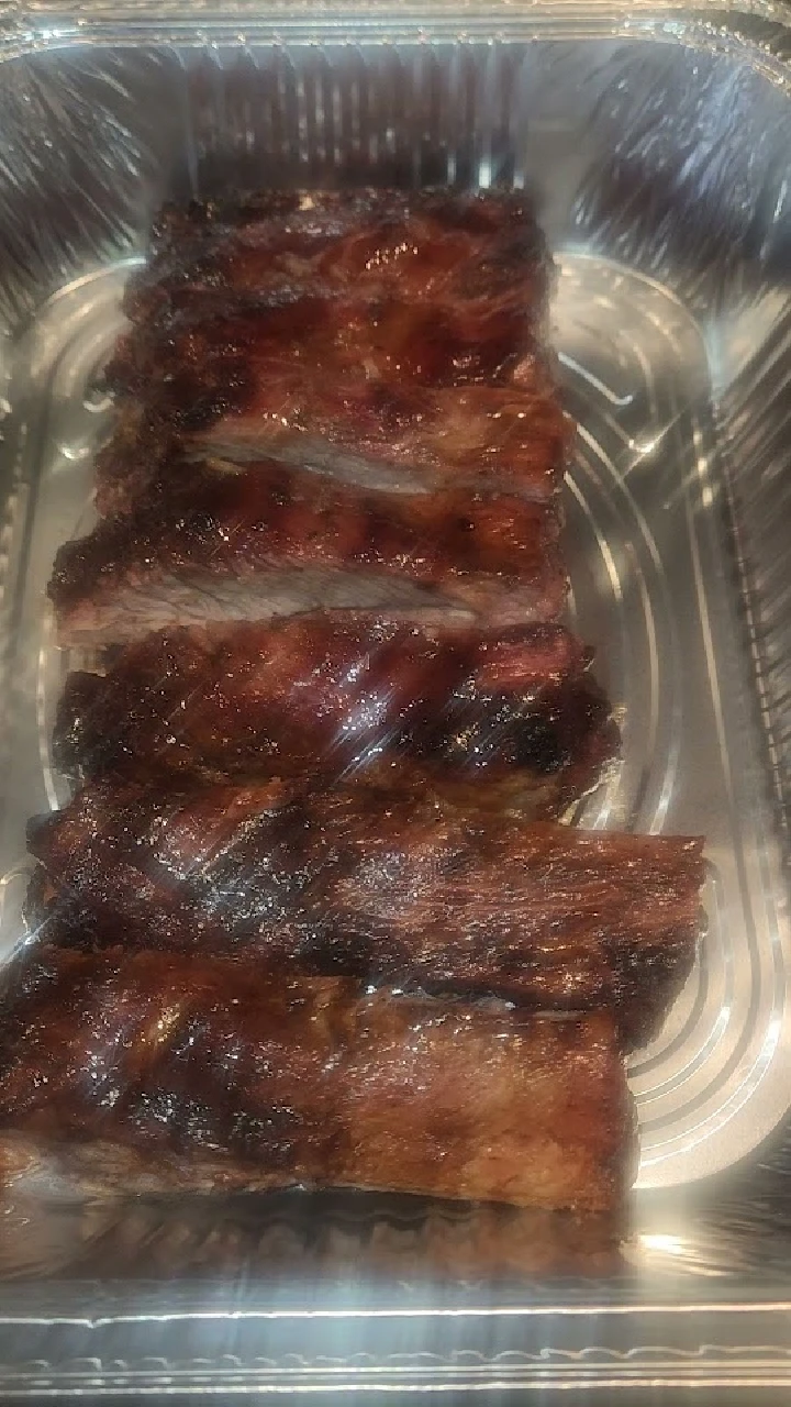 Grilled ribs in a silver serving tray.