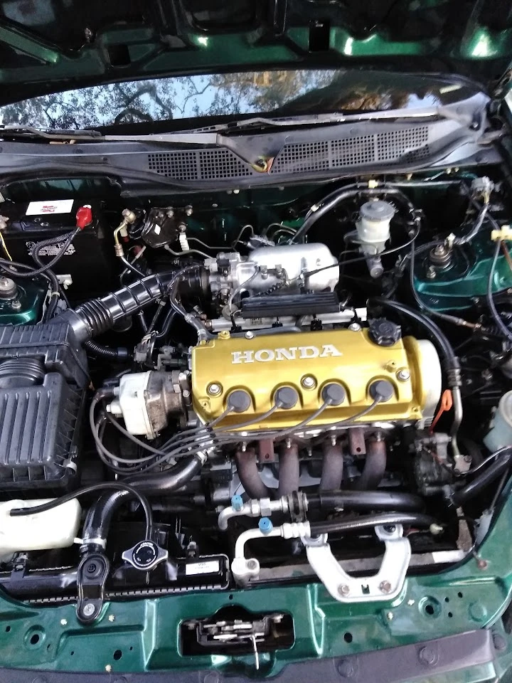 Honda engine with gold valve cover in a vehicle.