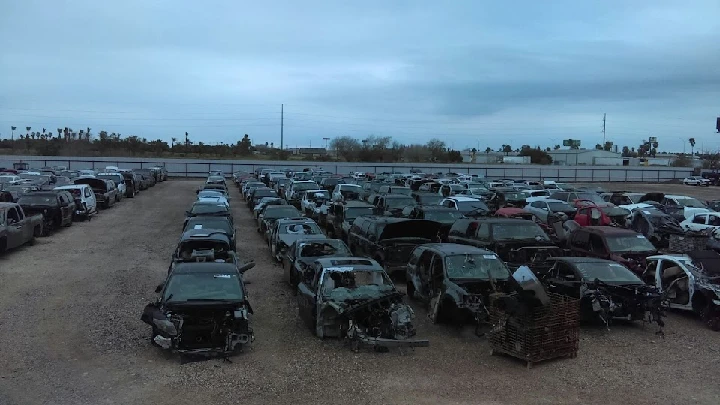 Junkyard with rows of dismantled vehicles.