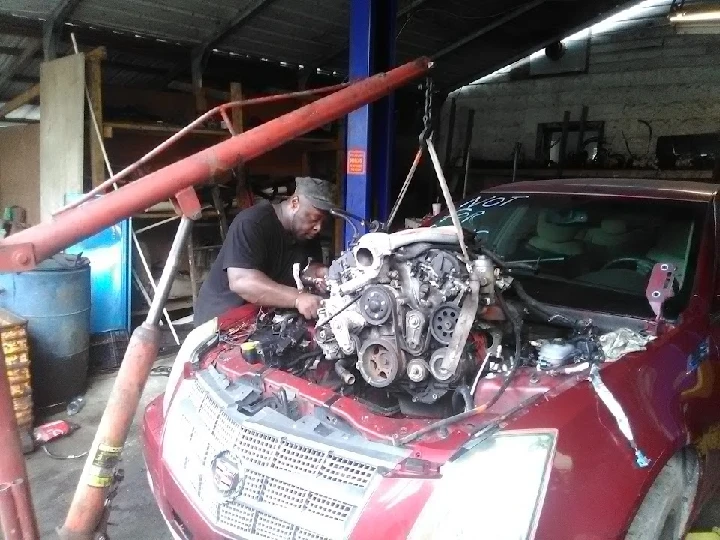 Mechanic working on car engine in auto parts shop.