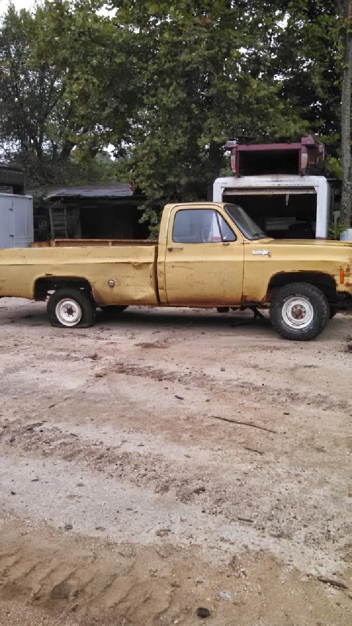 Old yellow truck in a wrecking yard.