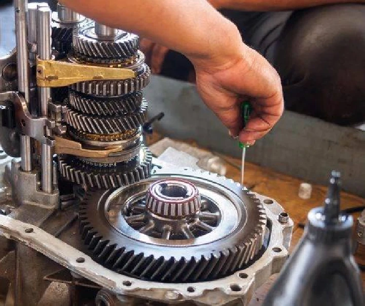 Person repairing a gear assembly in a workshop.