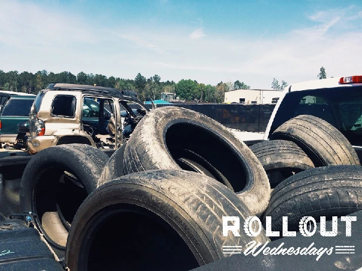 Piled tires in a junkyard under a clear sky.