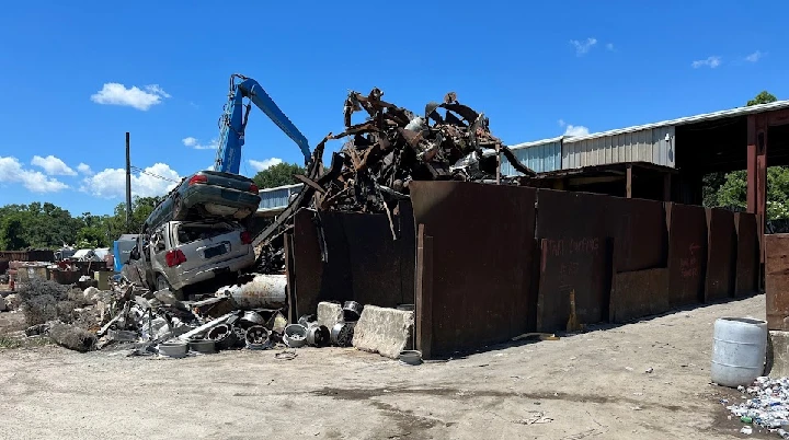 Recycling yard with vehicles and metal scraps.