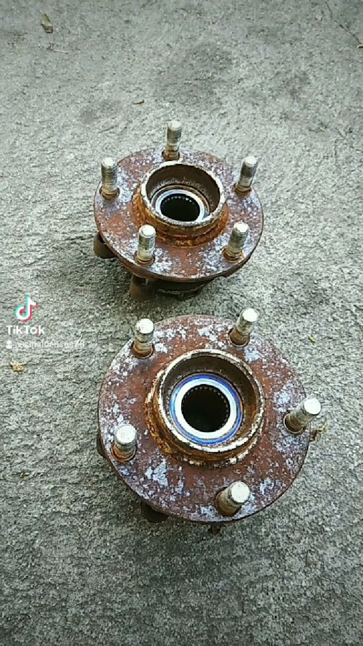 Rusty auto parts, two wheel hubs on a surface.