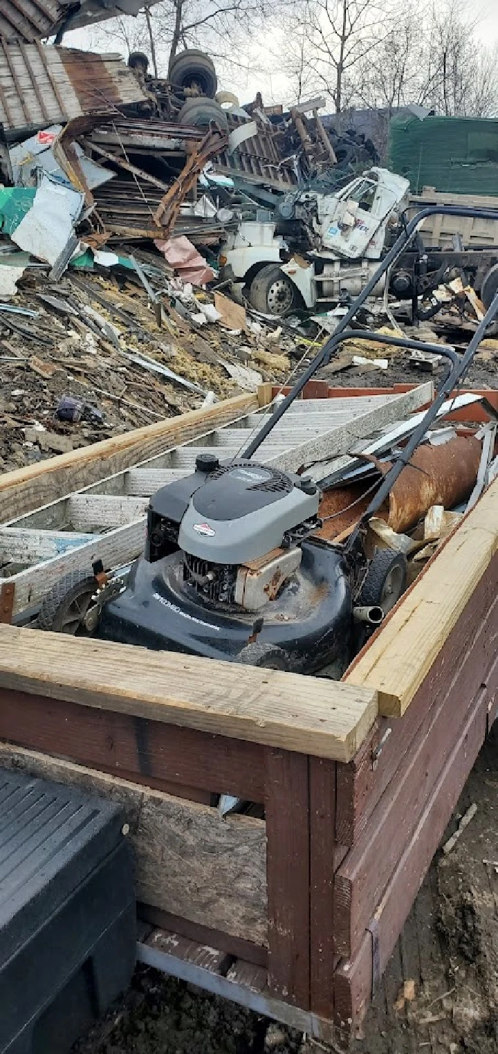 Scrap yard with discarded lawnmower and debris.