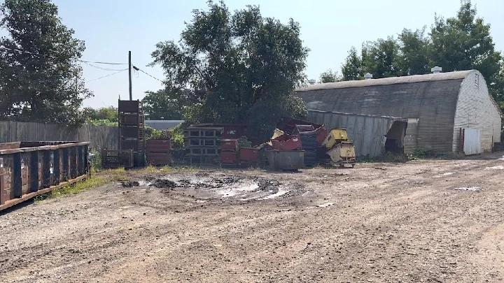 Scrapyard scene with metal containers and debris.