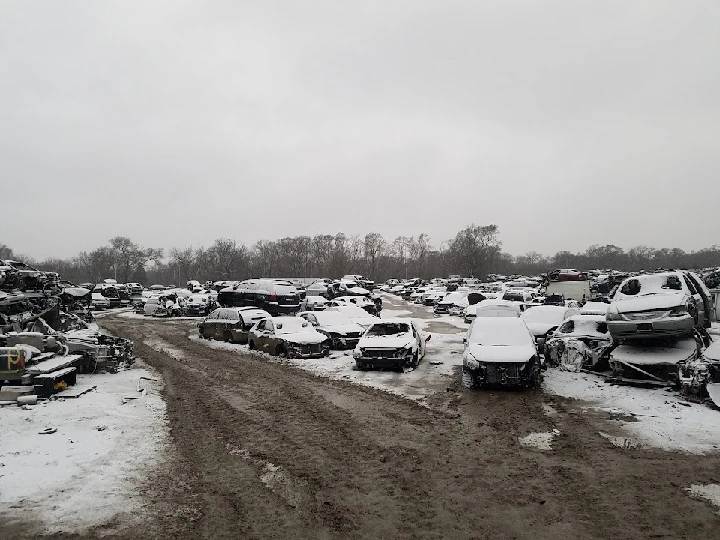 Snow-covered auto salvage yard with parked vehicles.