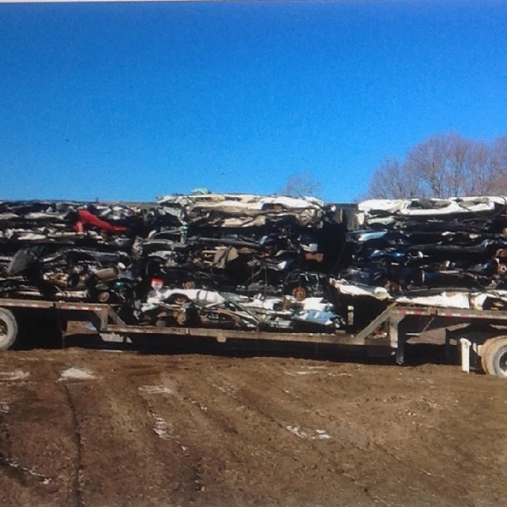 Stacks of crushed cars on a trailer in a yard.