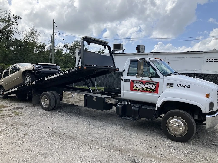 Tow truck with car loaded, Thompson JUNK CAR BUYER.