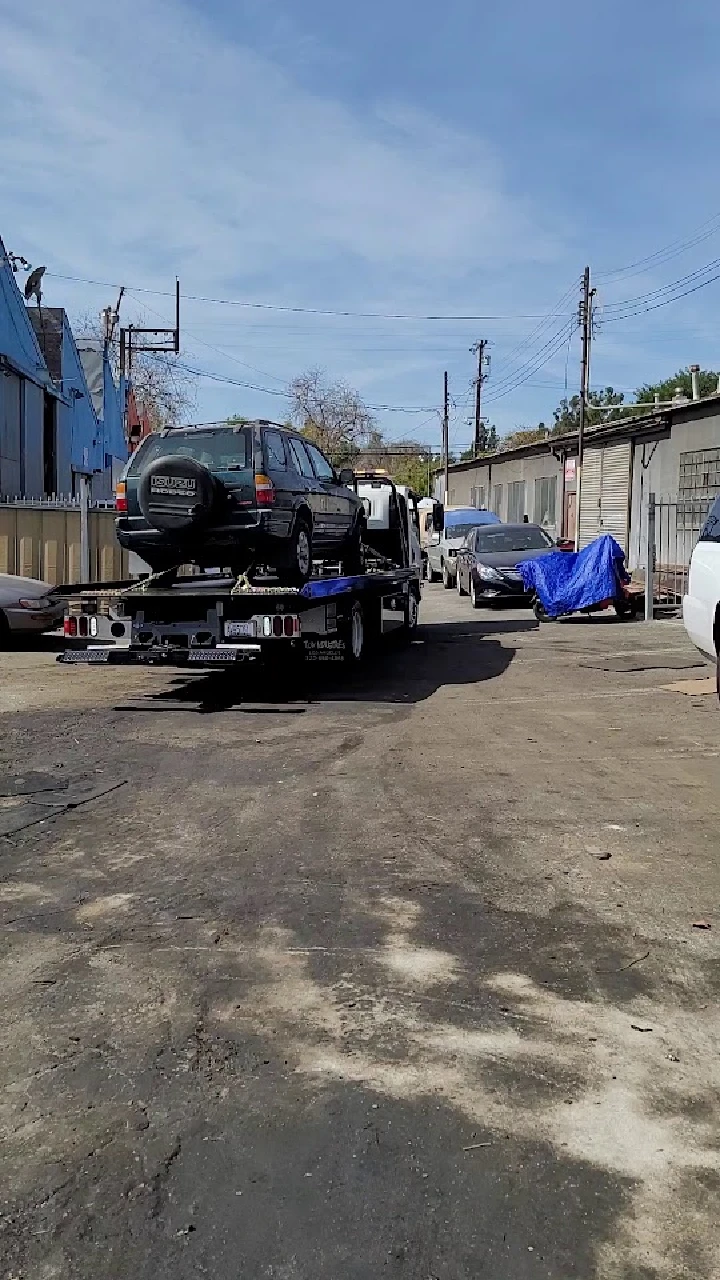 Tow truck loading a junk car in a yard.