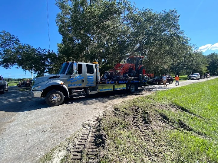 Tow truck loading junk vehicles by the roadside.