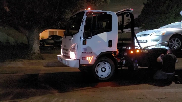 Tow truck picking up a vehicle at night.