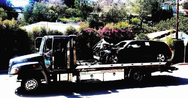 Tow truck transporting a damaged vehicle.