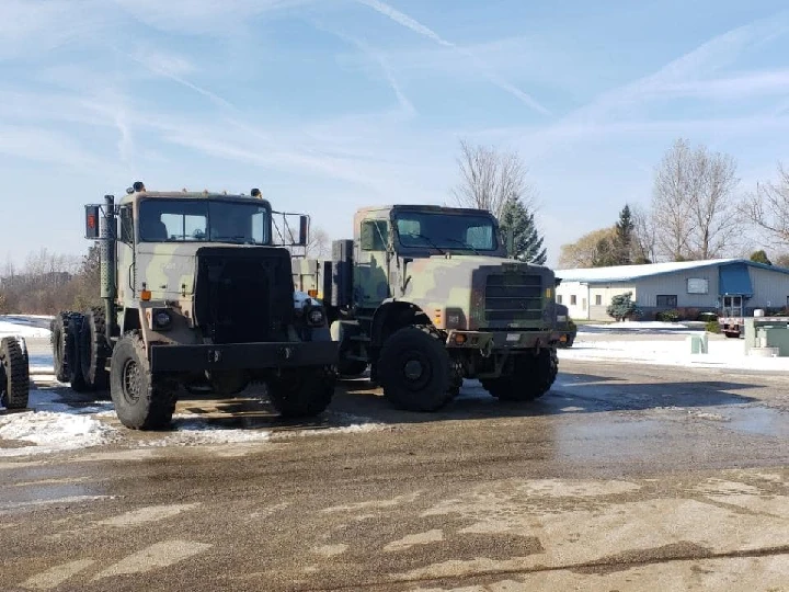 Two military trucks parked on a winter day.