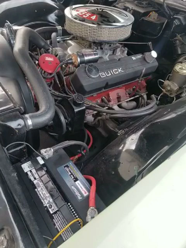 Vintage car engine with battery and components.